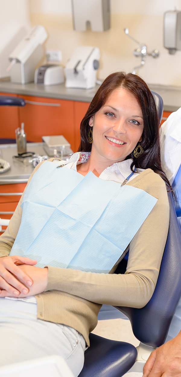 Junge lächelnde Frau auf Zahnarztstuhl in Zahnarztpraxis, mit sehr schönen und ästhetisch ansprechenden Zähnen.